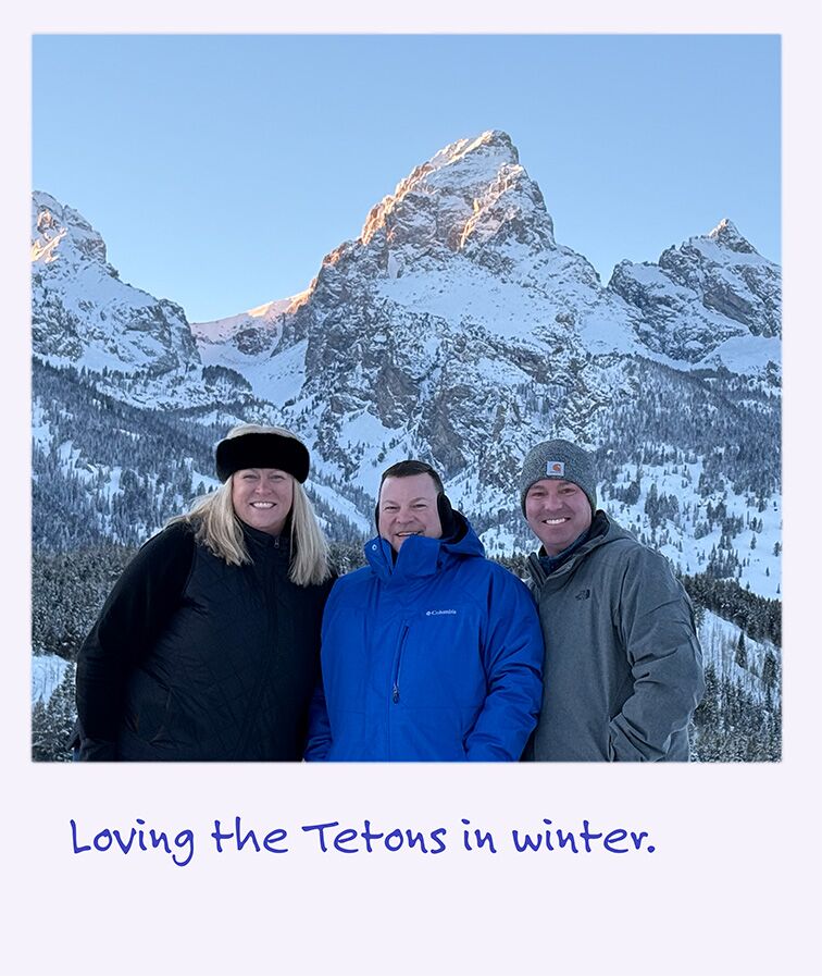 A polaroid image of smiling people in front of the snow-covered Grand Teton.