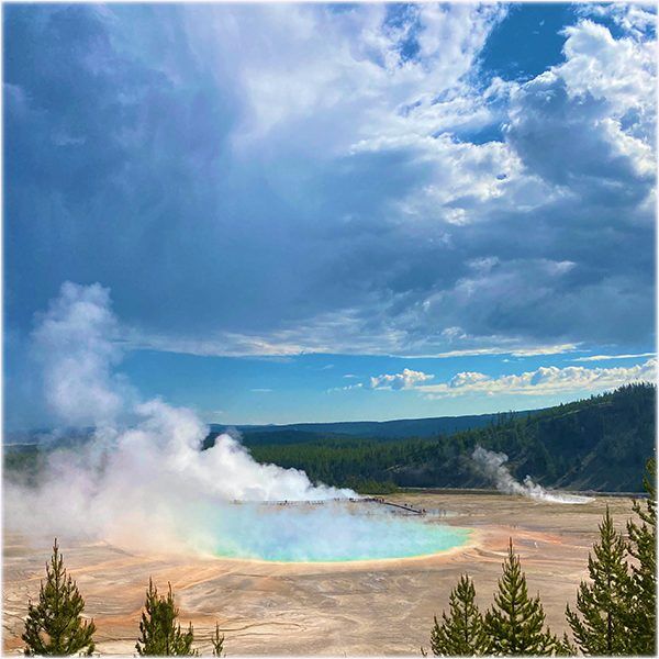 YellowstoneTourGrandPrismaticSpring Guides of Jackson Hole A man stands on a cooler to view wildlife over the top of a snow bank.